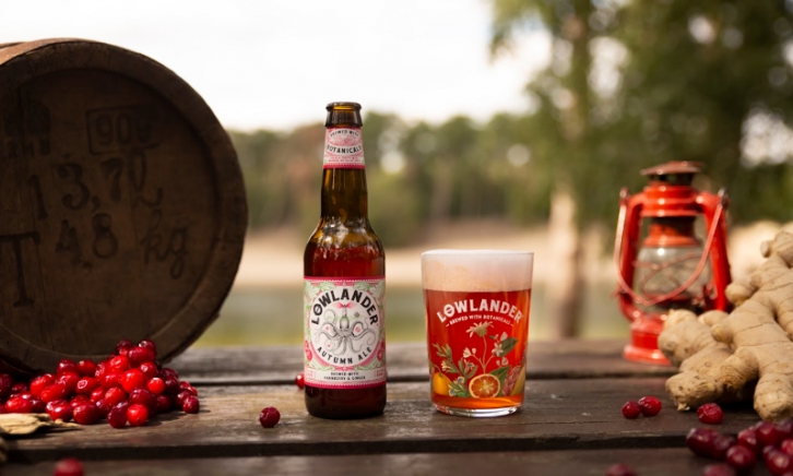 Lowlander Autumn Ale flesje en glas op tafel met cranberries en gember er omheen